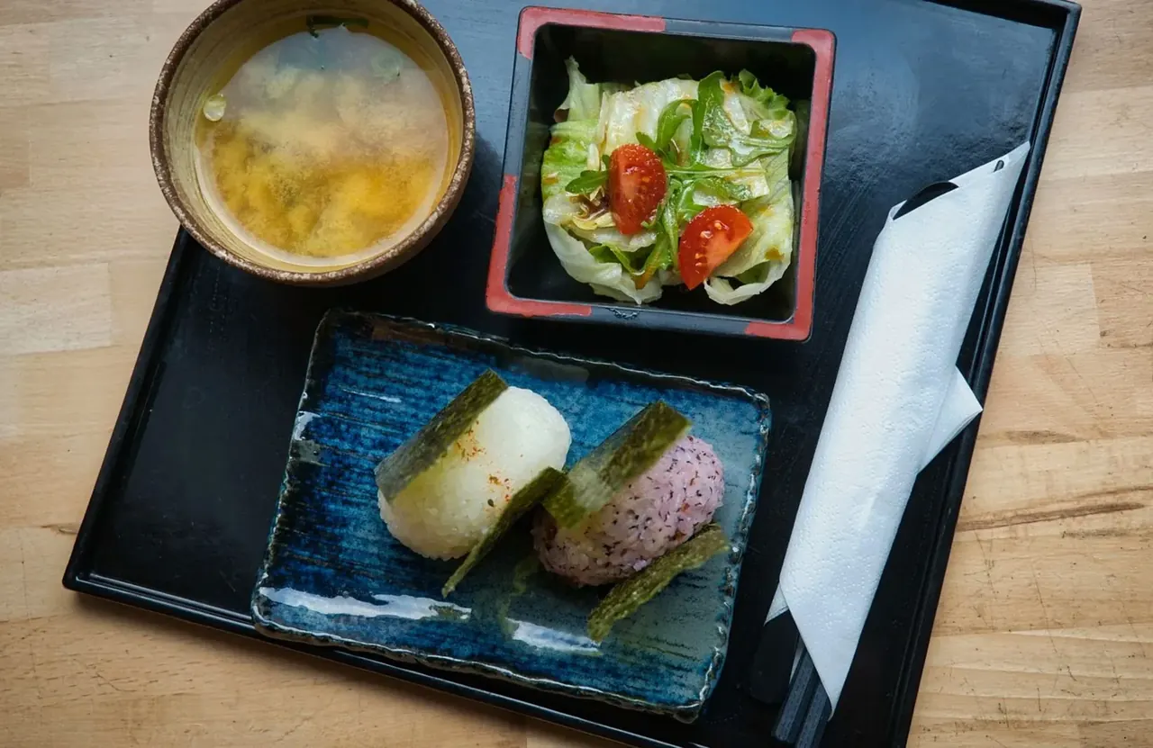 朝食のイメージ写真（味噌汁、サラダ、おにぎりを載せたお盆）