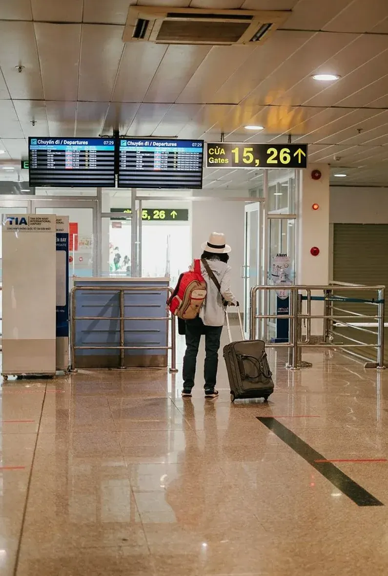 空港の構内でスーツケースを引いて歩く旅行者（イメージ写真）